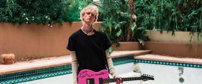 MGK promotional banner on Lickd, featuring the artist holding a pink electric guitar by a poolside, with a 'Just added' label and 'Listen Now' call to action